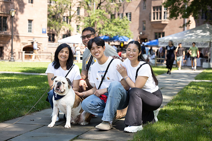 Student and family moving in on campus posing with Handsome Dan