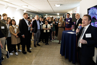 Attendees standing together listening to Dean of Yale College, Pericles Lewis, speaks into a microphone during the 2024 PLC Fall Gathering